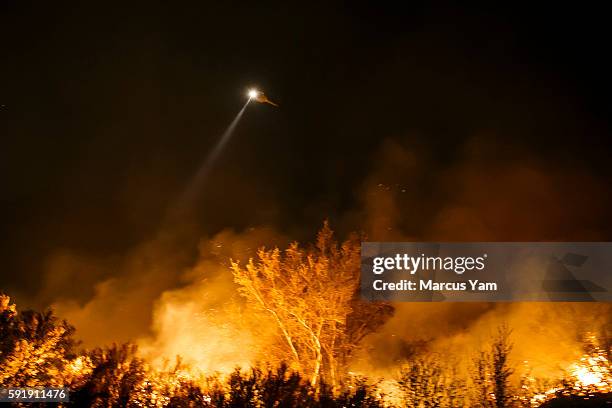 Firefighter helicopter shines a spotlight onto an area before making a water drop on the Blue Cut fire that is burning north of the Lyle Creek...