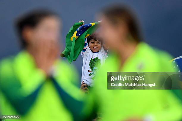 Young spectator watches as Martine Grael of Brazil and Kahena Kunze of Brazil celebrate winning gold in the Women's 49er FX class at the Marina da...