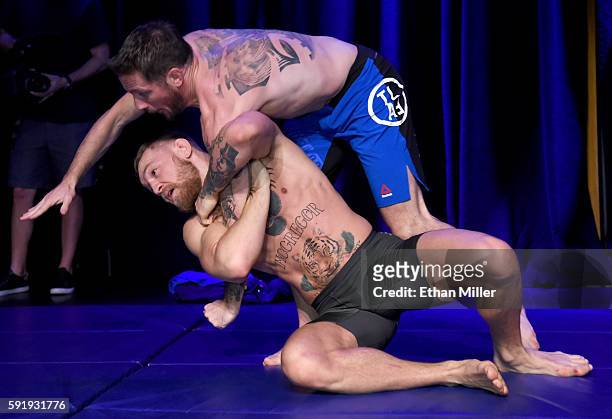 Featherweight champion Conor McGregor works out with his head coach John Kavanagh during an open workout for UFC 202 at Rocks Lounge at the Red Rock...