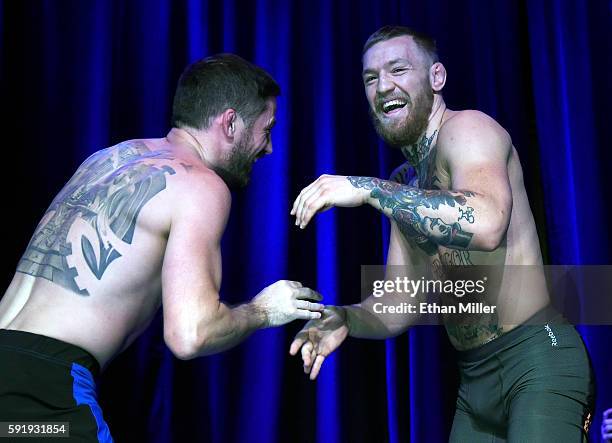 Featherweight champion Conor McGregor laughs as he works out with his head coach John Kavanagh during an open workout for UFC 202 at Rocks Lounge at...