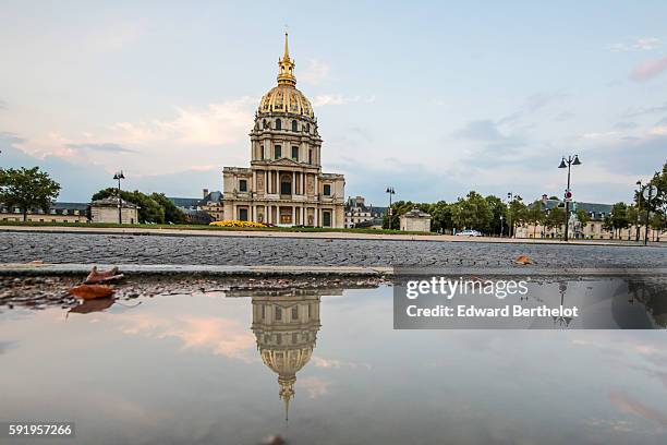 The Hotel des Invalides, reflects into a water puddle on a rainy summer day, during the evening, on August 18, 2016 in Paris, France.