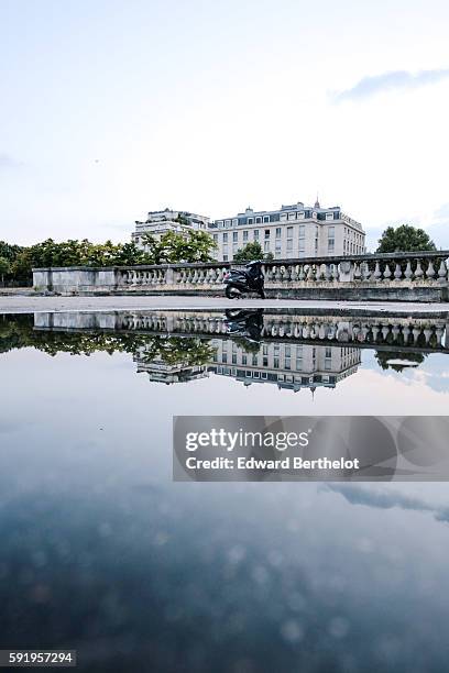 Paris buildings reflect into a water puddle on a rainy summer day, during the evening, near the bridge "Pont Alexandre iii " on August 18, 2016 in...