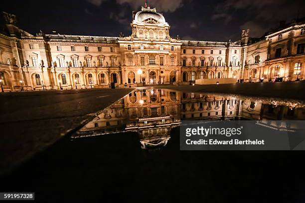 The Louvre museum reflects into a water puddle on a rainy summer day, during night time, on August 18, 2016 in Paris, France.