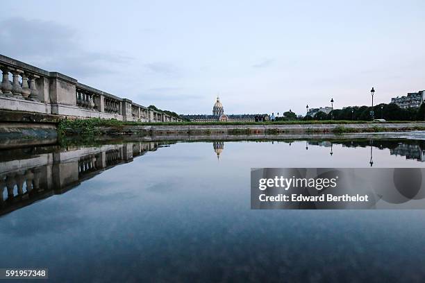 The Hotel des Invalides, reflects into a water puddle on a rainy summer day, during the evening, on August 18, 2016 in Paris, France.