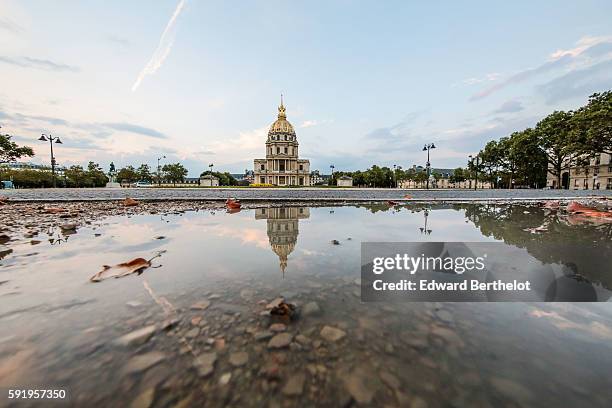 The Hotel des Invalides, reflects into a water puddle on a rainy summer day, during the evening, on August 18, 2016 in Paris, France.