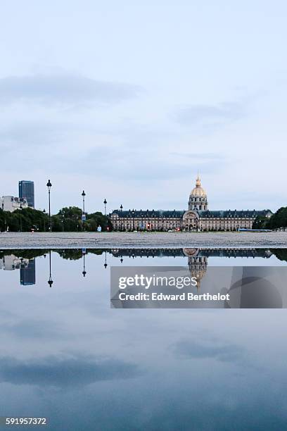 The Hotel des Invalides, reflects into a water puddle on a rainy summer day, during the evening, on August 18, 2016 in Paris, France.