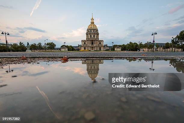The Hotel des Invalides, reflects into a water puddle on a rainy summer day, during the evening, on August 18, 2016 in Paris, France.