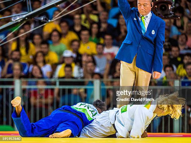 Referee Guoqiao Wang of China raises his arm for ippon as Kayla Harrison of the United States arm-locks former world champion, Audrey Tcheumeo of...