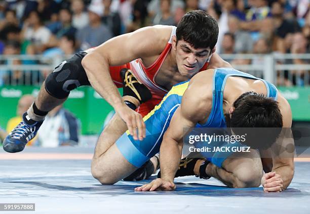 Iran's Hassan Aliazam Yazdanicharati wrestles with Kazakhstan's Galymzhan Usserbayev in their men's 74kg freestyle semi-final match on August 19...