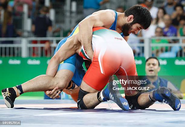 Iran's Hassan Aliazam Yazdanicharati wrestles with Kazakhstan's Galymzhan Usserbayev in their men's 74kg freestyle semi-final match on August 19...