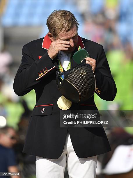 Britain's Nick Skelton wipes his face after getting his gold medal in the individual equestrian show jumping event at the Olympic Equestrian Centre...