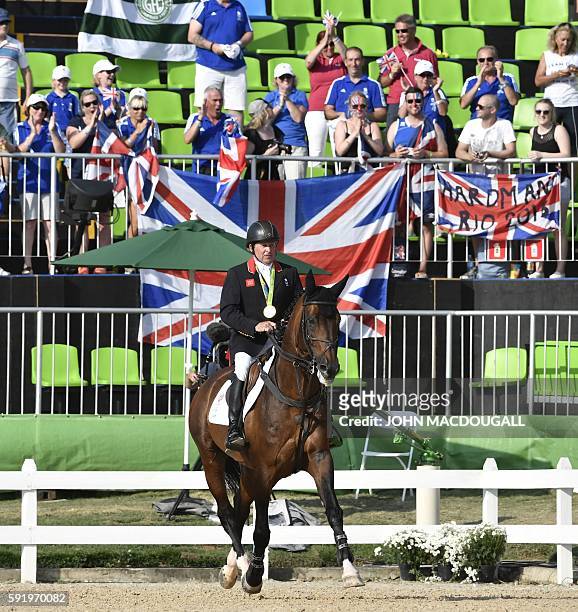 Britain's Nick Skelton on his horse Big Star rides with his gold medal after winning the individual equestrian show jumping event at the Olympic...