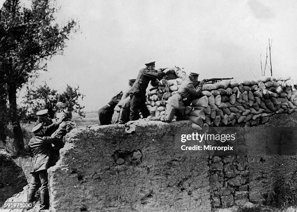 German troops seen here sniping at a Russian patrol from behind a breastworks built of sandbags as medic's see to an injured soldier. Location not...