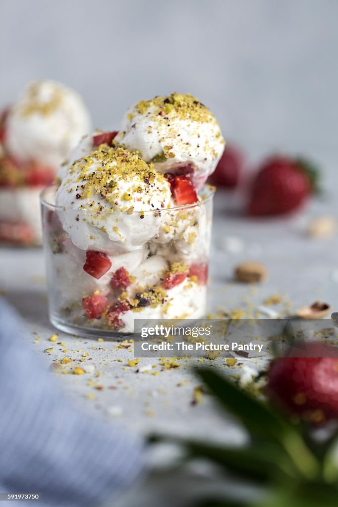 A couple scoops of coconut milk and cashew ice cream topped off with strawberries and pistachio crumbs