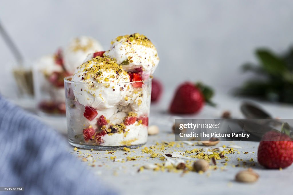 A couple scoops of coconut milk and cashew ice cream topped off with strawberries and pistachio crumbs