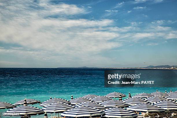 beach umbrellas on beach of the city of nice - jean marc payet stock pictures, royalty-free photos & images