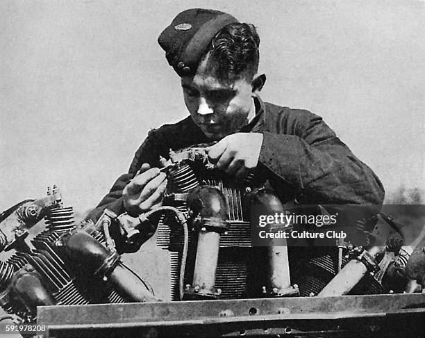 Apprentice mechanic at work on the ground. Caption reads: A boy trainee assembling an aeroplane engine