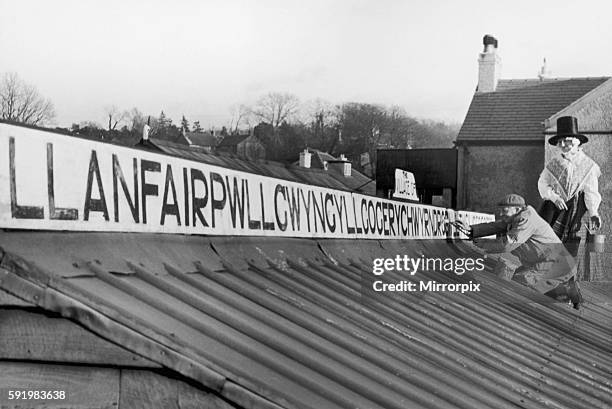 Mr and Mrs Jones of Llanfairpwllgwyngyllgogerychwyrndrobwllllantysiliogogogoch on the island of Anglesey, North Wales paint a sign bearing the long...