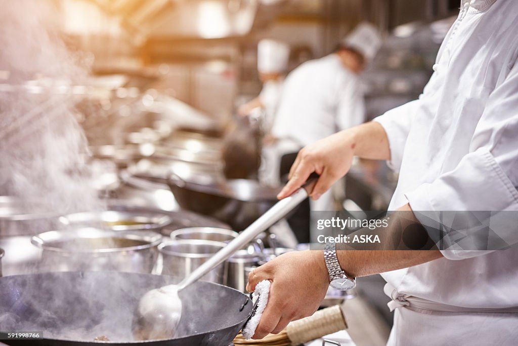 Küchenchef in restaurant kitchen at Herd mit Kochgeschirr