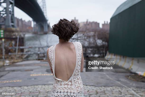 woman in low-back dress walking in industrial area - zona lombare foto e immagini stock