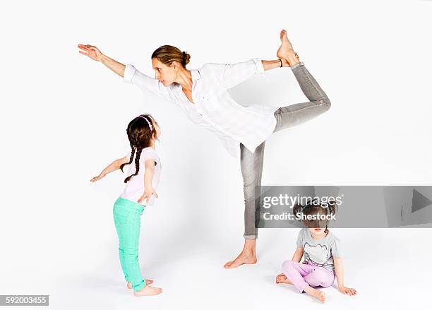 mother practicing yoga with playful daughters - sports imagery 2012 fotografías e imágenes de stock