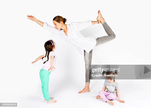 mother practicing yoga with playful daughters - daily sport girls bildbanksfoton och bilder
