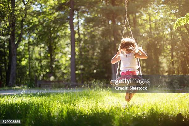 girl sitting on swing in field - rope swing stock pictures, royalty-free photos & images