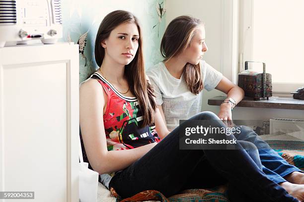 serious sisters sitting on bed - siblings arguing stock pictures, royalty-free photos & images