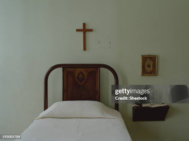 crucifix over bed in simple bedroom - crucifixion stock-fotos und bilder