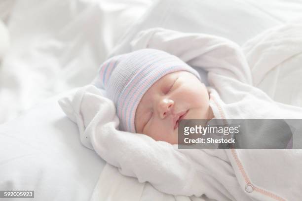 caucasian newborn girl laying on bed - knit hat stock pictures, royalty-free photos & images