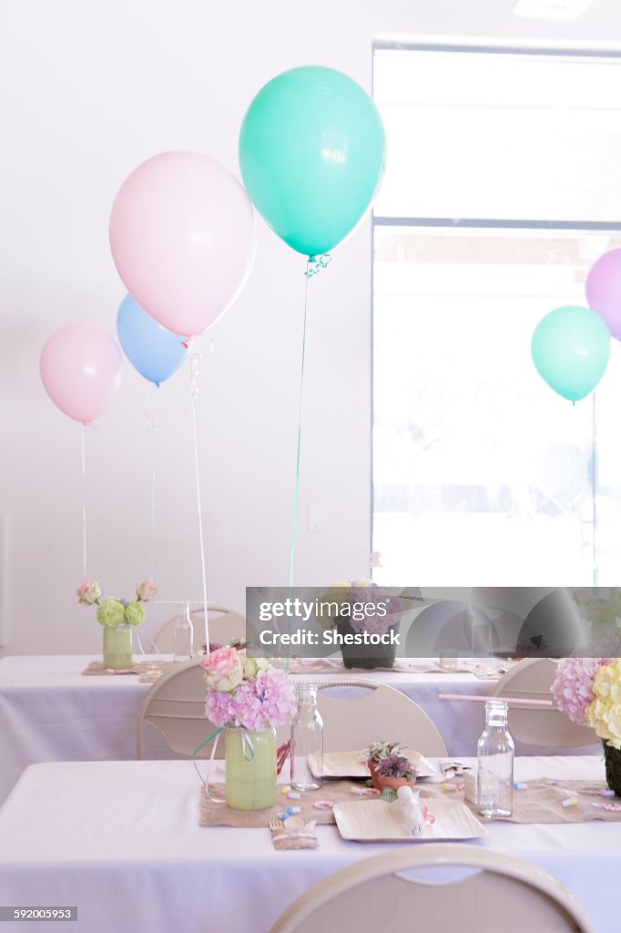 Place settings on party tables under balloons