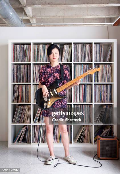 taiwanese woman playing electric guitar near record collection - amplificateur photos et images de collection