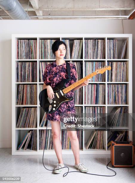 taiwanese woman playing electric guitar near record collection - record player fotografías e imágenes de stock