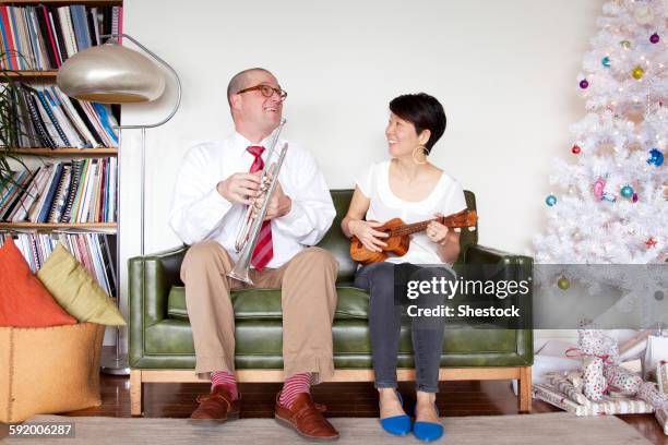 couple playing music near christmas tree - acoustic christmas stock pictures, royalty-free photos & images