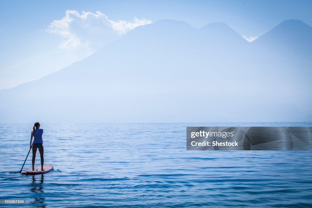 Girl standing on paddleboard in remote lake