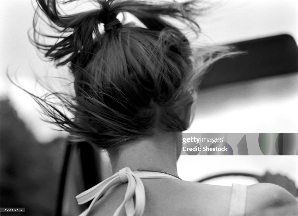 Rear view of woman driving car in wind