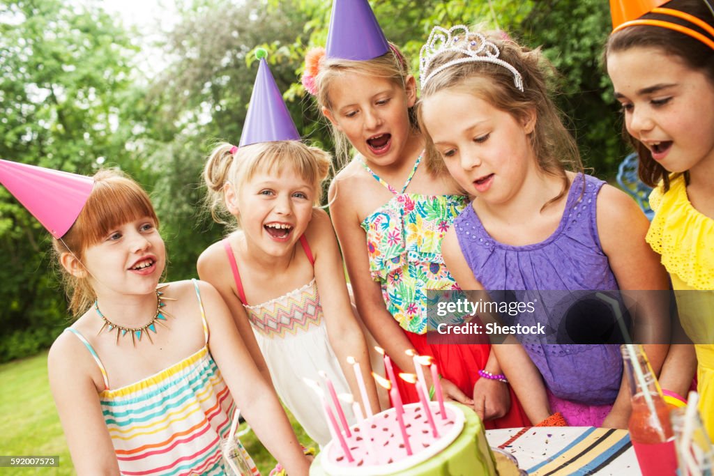 Girls admiring cake at birthday party outdoors