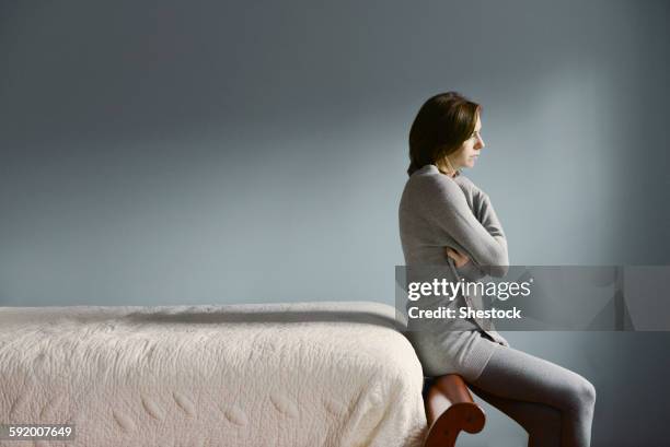 sad caucasian woman sitting on bed frame - bed side view stock pictures, royalty-free photos & images