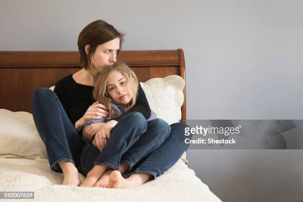 caucasian mother cuddling daughter on sofa - londonderry new hampshire ストックフォトと画像