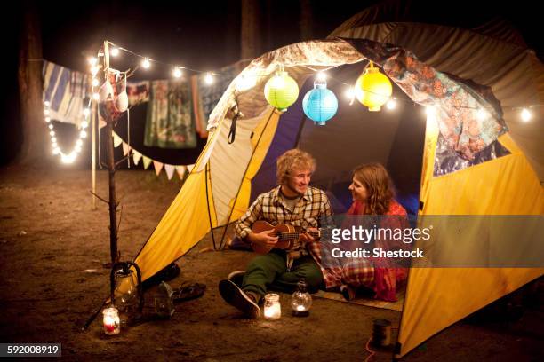 couple playing music in camping tent at night - entertainment tent ストックフォトと画像