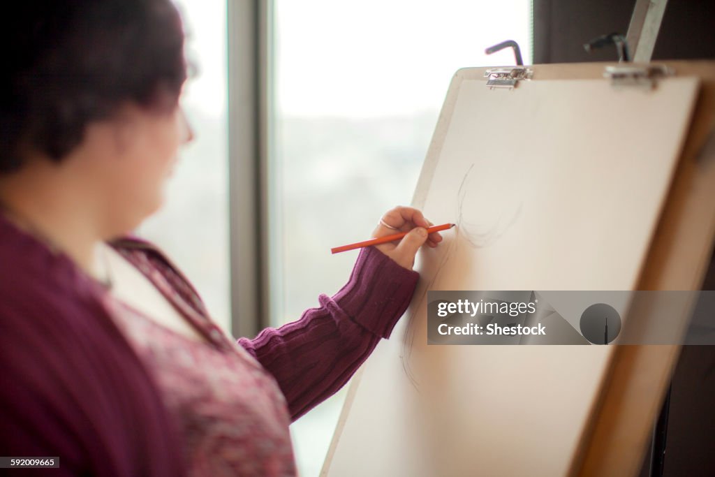 Caucasian artist sketching on easel