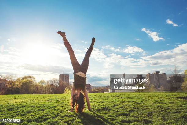 caucasian woman doing handstand in urban park - cartwheel stock pictures, royalty-free photos & images