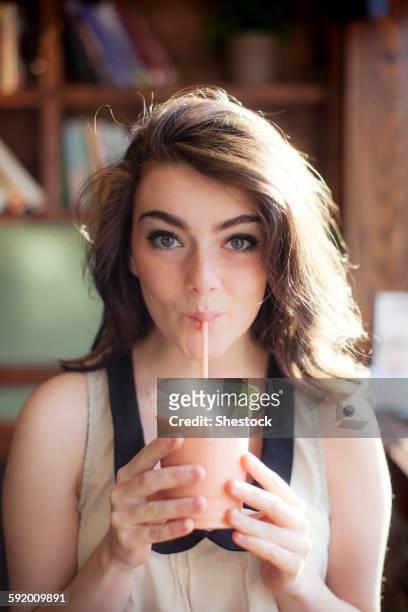 caucasian teenage girl drinking smoothie in cafe - rietje stockfoto's en -beelden