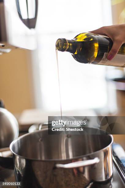 close up of woman pouring olive oil into pot - oil bottle stock pictures, royalty-free photos & images