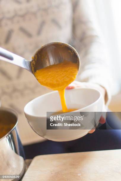 close up of woman ladling bowl of soup - utensile di portata foto e immagini stock
