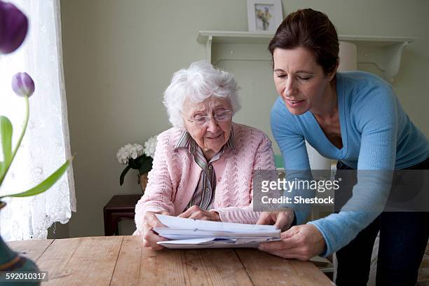 woman reading to mother at table - mature woman daughter stockfoto's en -beelden