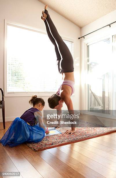 woman practicing yoga and helping daughter with homework - yoga rug photos et images de collection