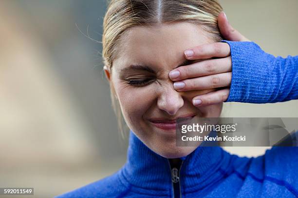 young woman squinting at discomfort in eye - entrecerrar los ojos fotografías e imágenes de stock