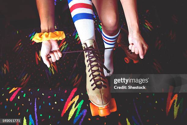 high angle view of woman lacing up roller-skates - indoor skating stock pictures, royalty-free photos & images