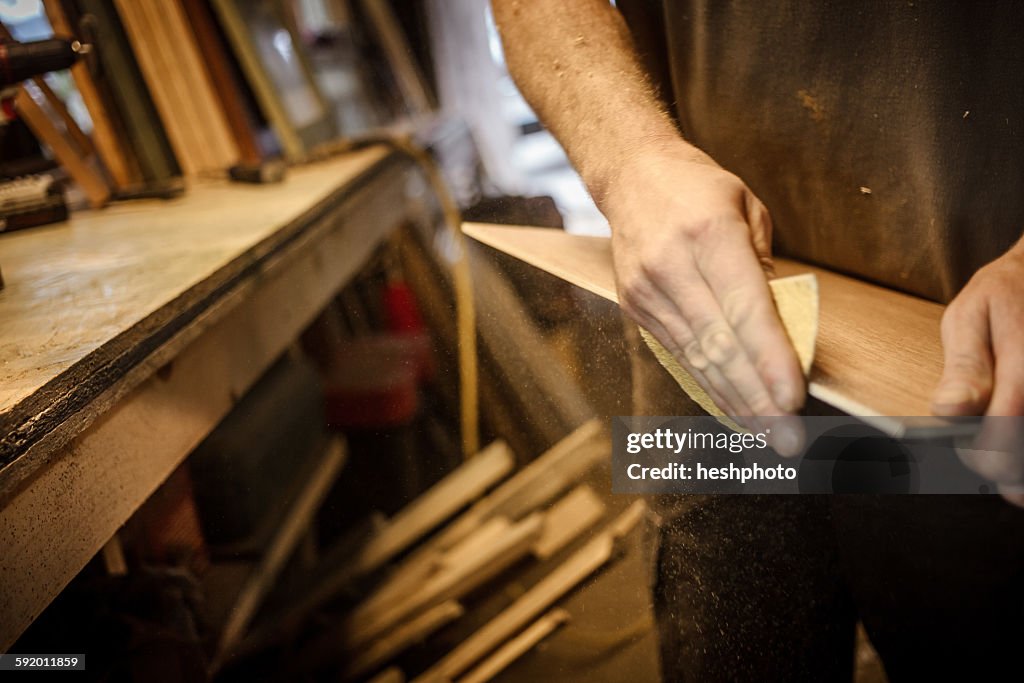 Wood artist in workshop, sanding wood, close-up